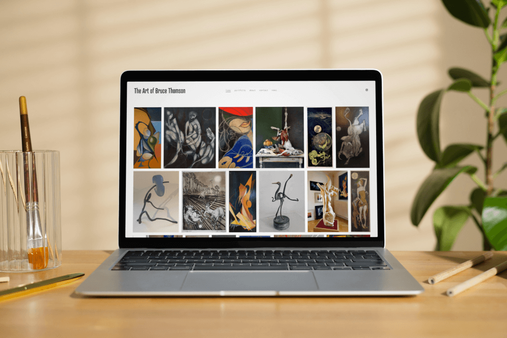 The Art of Bruce Thomson website displayed on a laptop in a studio setting
